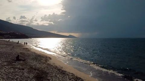 Aerial flight at beach: Flying backwards over ocean with dark clouds on horizon Stock Footage 146290954