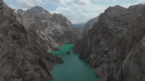 Aerial flight between cliffs above turquoise Kel-Suu lake, Kyrgyzstan Stock Footage 347241339