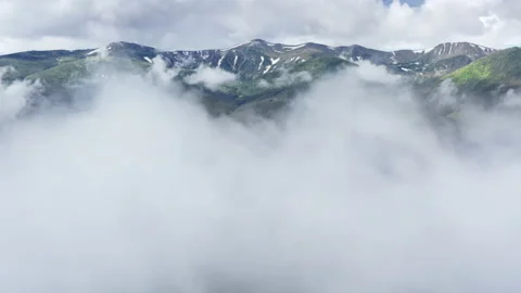 Aerial flight deep inside clouds high above mountain tops. High peaks covered by Stock Footage 135323249