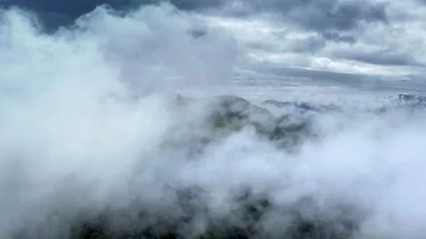 Aerial flight deep inside clouds high above mountain tops. High peaks covered by Stock Footage 135323655