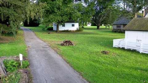 Aerial flight down path pass woodpile to outbuildings on the Herr House Stock Footage 102143429