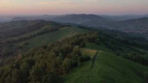 Aerial flight of a drone over a mountain In the evening. Small town nearby Stock Footage 249444323