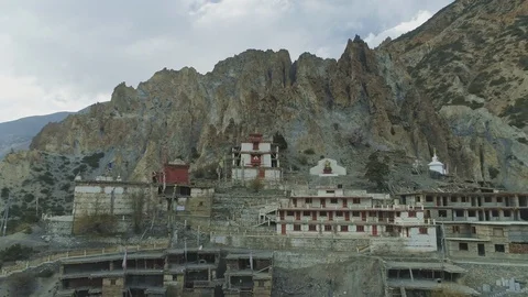 Aerial flight at empty windy Braga monastery nesting under crest cliffs, Nepal Stock Footage 124679409