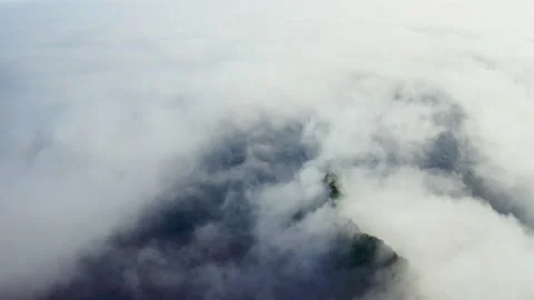Aerial flight over endless white clouds covering dark shoreline with green hills Stock Footage 169091346