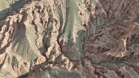 Aerial flight over eroded red sandstone badlands, Kok-Moinok Canyons, Kyrgyzstan Stockbeeldmateriaal 347239541