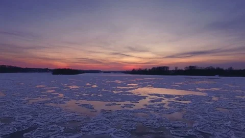 AERIAL: Flight over a frozen river during a blood-red sunset. Colorful landscape Stock Footage 83828811