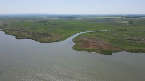 Aerial flight over a large lake and river that cuts through green farm fields. Stock Footage 156636795