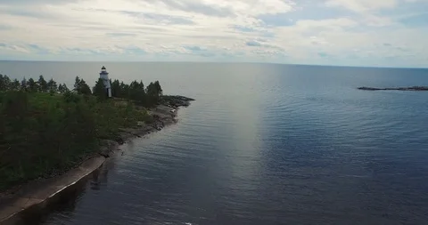 Aerial flight over lighthouse on cape against huge lake  Stock Footage 100981464