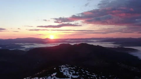 Aerial flight over mist during sunrise in mountains. Snowy Mountain Range Sil Stock Footage 164722976