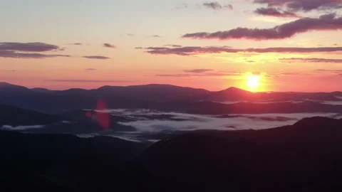 Aerial flight over mist during sunrise in mountains. Snowy Mountain Range Sil Stock Footage 165752007