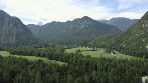 Aerial flight up over a mountain valley with meadows and pastures. Video stock 217374612