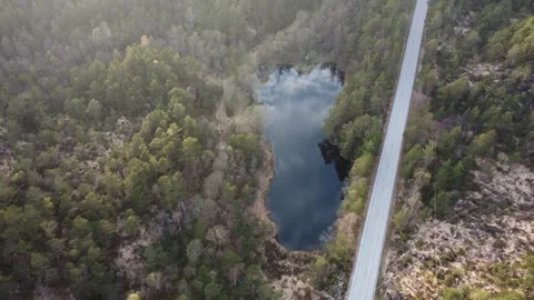 Aerial flight over a remote road and a lake reflecting the clouds in a Norwegian Video stock 335199210