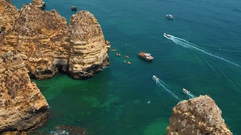 Aerial flight over rock formations in Lagos, Portugal birds flying motor boats Stock Footage