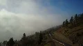 Aerial flight over sunny mountain road with traffic at clouds altitude 4k 4k or 4k+ Resolution