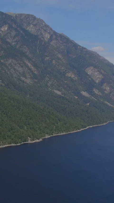 Aerial flight over Teletskoye Lake coast and taiga slopes in Altai Russia Video stock 346556447