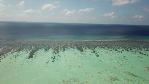 Aerial flight over turquoise lagoon and coral reef wall to deep ocean Maldives Stock Footage 342431470