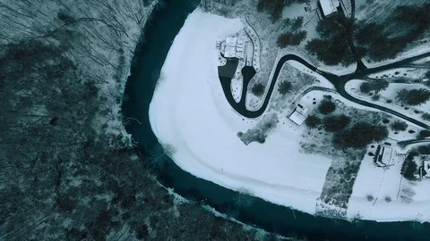 Aerial Flight over Winding River in Winter Forest Dark Snow Storm Stock Footage 76236242