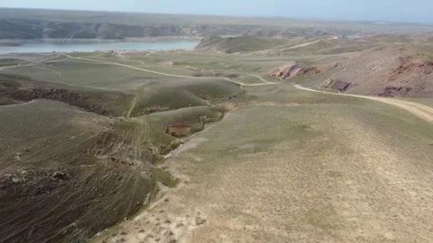 Aerial Flight Over Winding Road and Green Hills by Reservoir, Kazakhstan Stock Footage 332985080