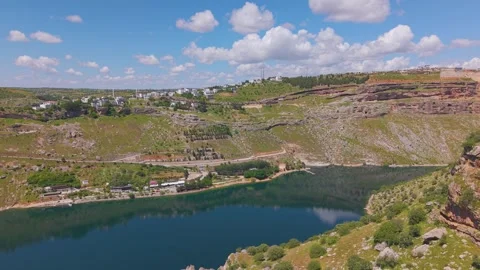 Aerial Flight from Rocky Cliffs Toward a Scenic Lakeside Village Video stock 340989662