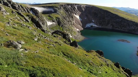 Aerial flight sideward under emerald mountain lake. Altai. Video stock 103371420