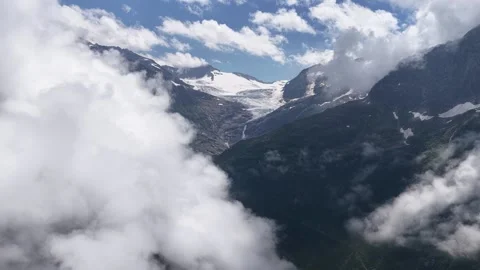 Aerial flight through clouds revealing majestic mountain glacier Stock Footage 317719834