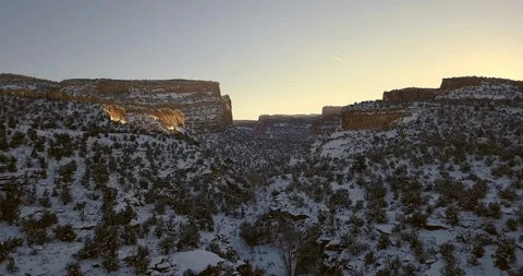 Aerial flight through sunset desert canyon with golden light on red rocks Video stock 101845127