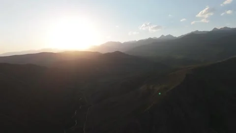 Aerial flight toward the setting sun over mountains, Kyrgyzstan Stock Footage 347240115