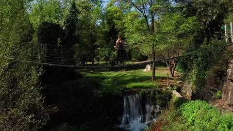 Aerial flight under the bridge view of girl standing on suspension bridge drone. Stock Footage 122670890