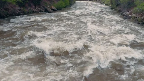 Aerial: Floating down a river with spring melt in a forest. Colorado, USA. Stock Footage 130292501