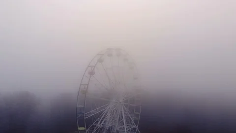 Aerial fly around empty and stopped ferris wheel in mist, look very mystery Stock Footage 105806719