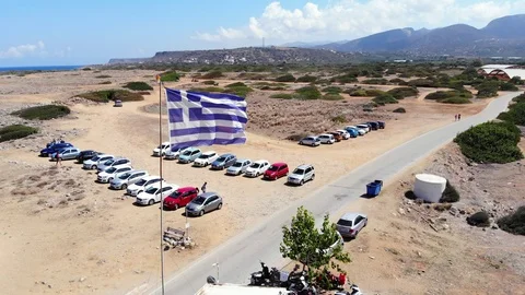 Aerial fly around Greece flag fluttering on sea wind, Crete Stock Footage 100757003