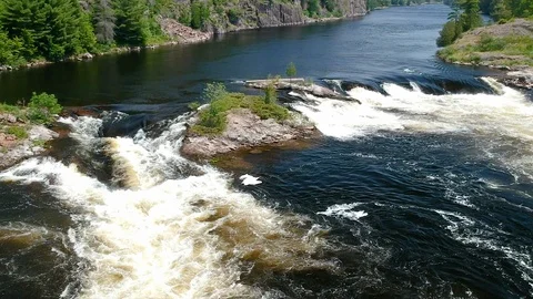 Aerial: fly close towards waterfall low above river with steep rocky shores Stock Footage 112359105