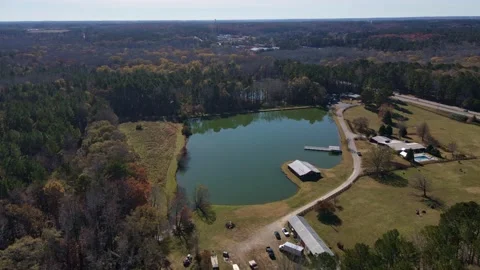 Aerial fly to green odd shaped lake with road and trees barn beside lake Stock Footage 170721485