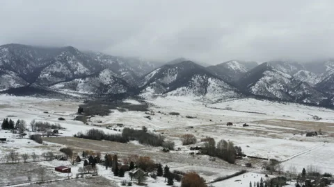 Aerial fly over fields with snow and mountains behind Stock Footage 165248673