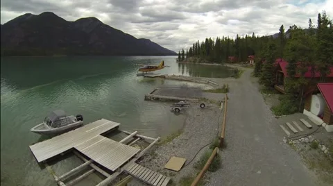 AERIAL FLY OVER OF FLOAT PLANE AT DOCK ON BEAUTIFUL LAKE IN CANADA Stock Footage 62758252