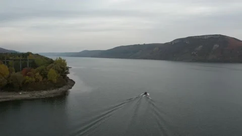 Aerial fly over river in canyon. Boat sailing on a wide river, rear view from Stock Footage 163825331