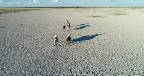 Aerial fly over view of a Group of horse riders cantering on the Makgadikgadi Stock Footage 107270703