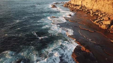 Aerial fly over of waves breaking on cliff side rocks Stock Footage 88671935
