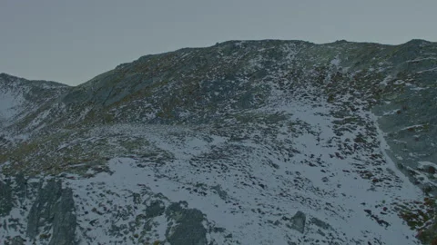 Aerial fly up tussock ridge with patchy snow and rock Stock Footage 155478460