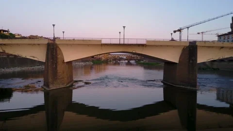 Aerial fly under Arno River Bridge to reveal Ponte Vecchio in Florence, Italy Видео 137091257