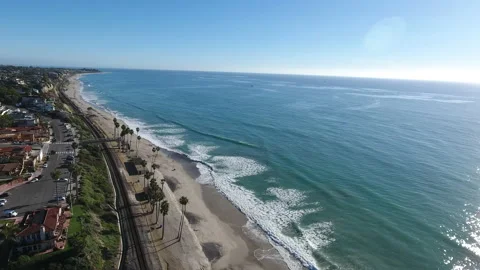 Aerial fly waves rolling in next to train tracks along the coast Stock Footage 157167907
