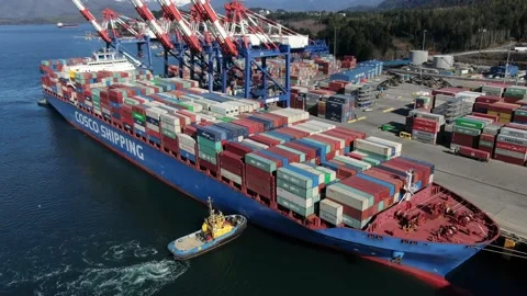 Aerial: Flyby of container ship preparing to depart from container terminal Stock Footage 149780111