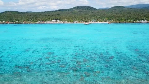 Aerial flying along outer reef looking back at tropical island 库存影片 107085658