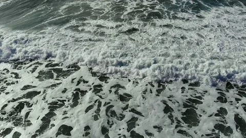 Aerial flying back view over splashing waves motion on orange sandy sea beach Stock Footage 120087578