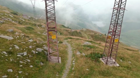 Aerial Flying Between High Voltage Pylon at Mountains Stock Footage 139708173