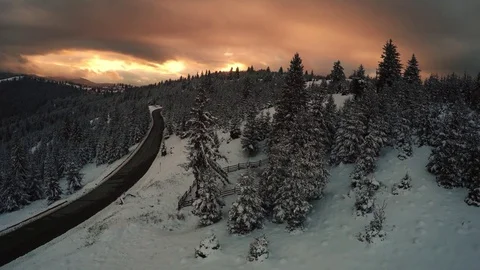 AERIAL: Flying close to trees in winter landscape at sunset with a colorful sky. Stock Footage 70418136
