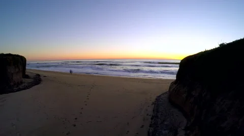 Aerial flying down a dried sand riverbed with ocean and sunset in background Stock Footage 60053507