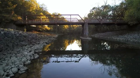 Aerial flying drone over a small river and under a bridge Stock Footage 68560197