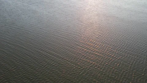 Aerial flying forward looking down onto a lake with waves reflecting the morning Stock Footage 220289209