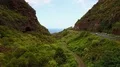 Aerial flying a green valley to coast between mountains with road and pathway 4k 4k or 4k+ Resolution